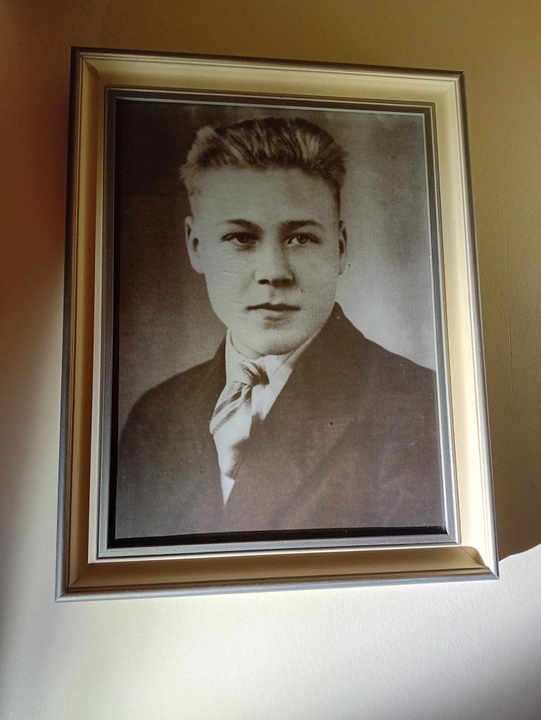 Kuva: Enni Ylenius (2025). Valokuvapotretti tuntemattomasta nuoresta miehestä, josta tuli kotimme vahtimestari.